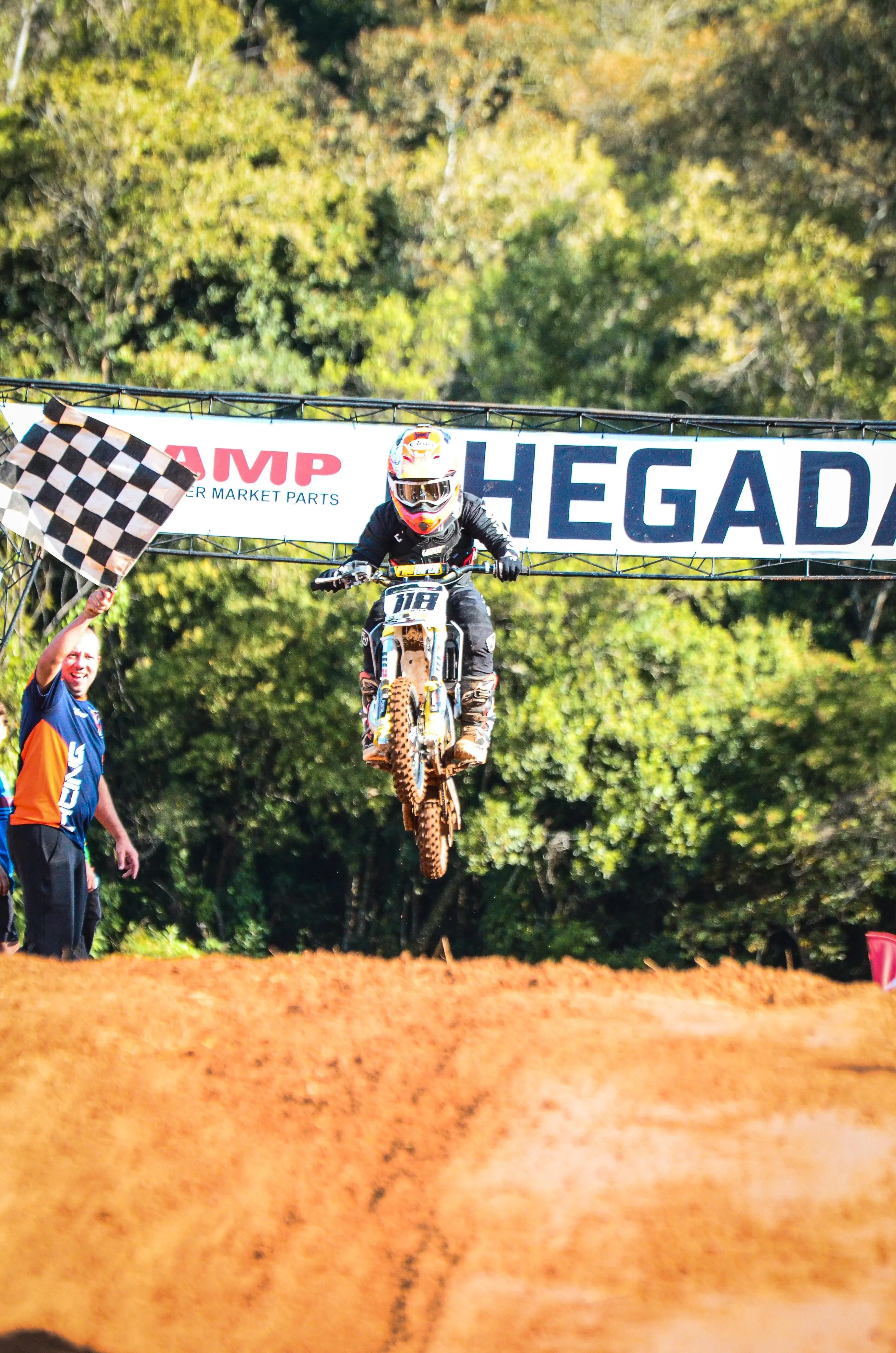 A young motocrosser crossing the finish line mid-jump.